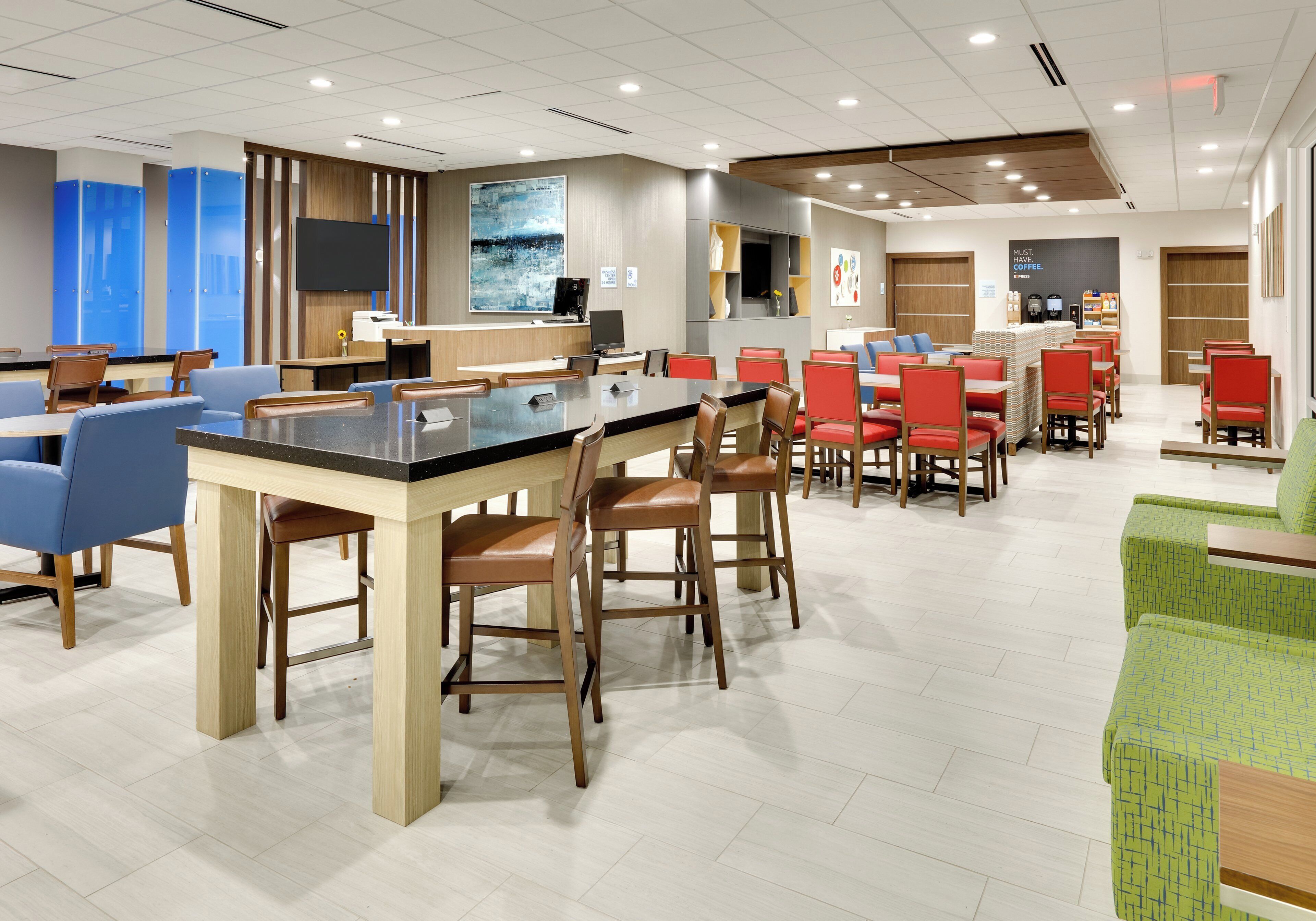 A modern dining area with a central bar, multiple seating options including booths and tables, and a large abstract painting on the wall.