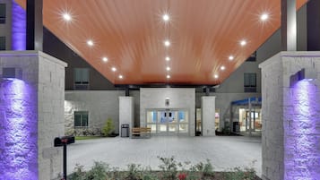 A modern building entrance with a sloped roof, a fire lane, and a gated entrance.