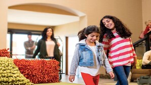 A group of people walking in a lobby with a display of colorful textiles.