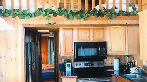 A wooden cabin with a kitchen featuring a microwave, stove, and sink.