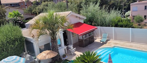 A residential property with a swimming pool, outdoor seating, and lush greenery.