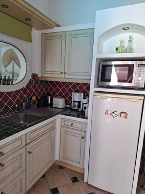 A kitchen with a microwave, coffee maker, and a refrigerator.
