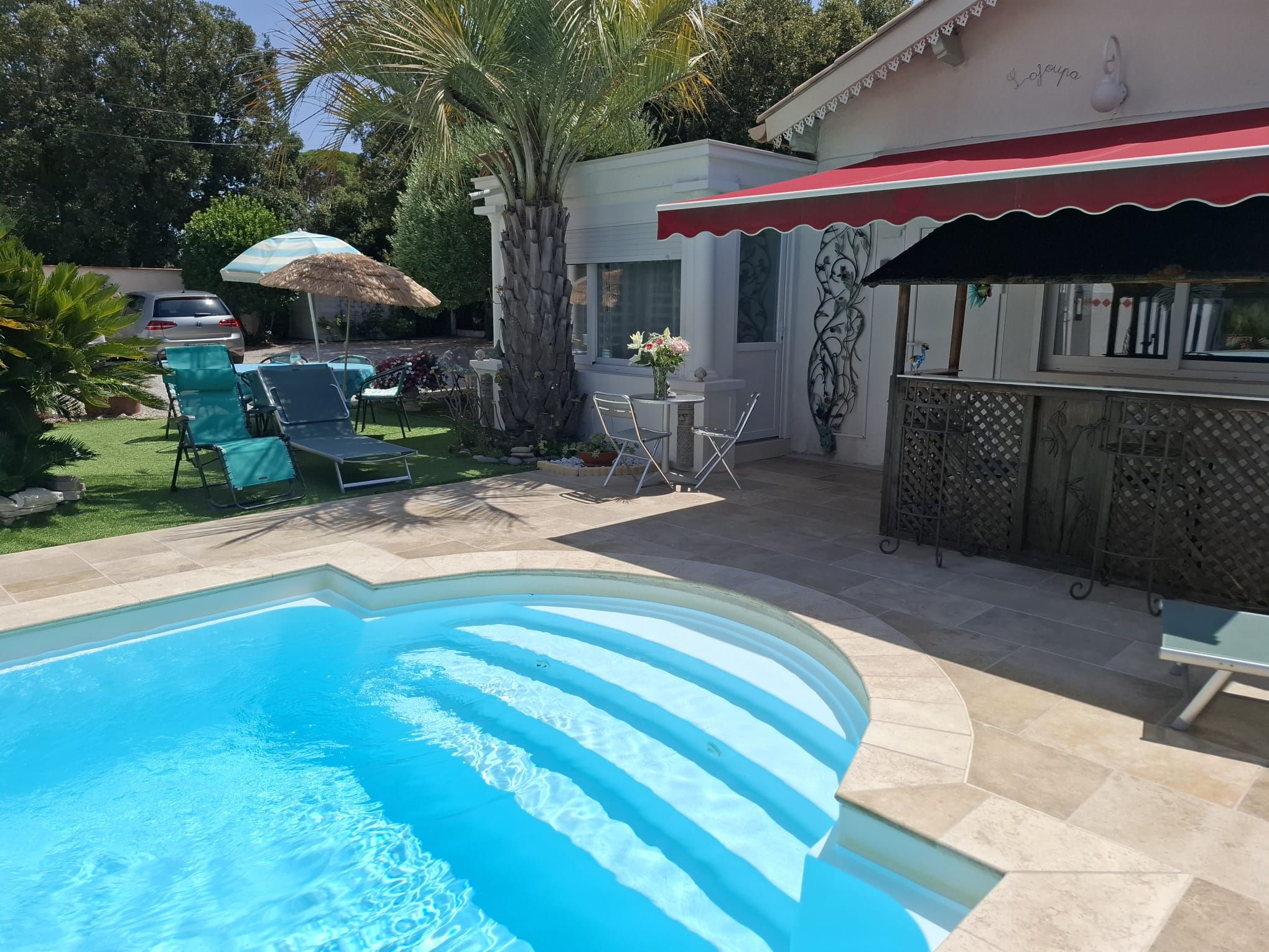 A swimming pool with a stone deck, outdoor seating, and a bar area.