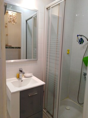 A bathroom with a white sink, mirror, and shower. - Small 30m2 house for 2 people on private property with swimming pool (Fréjus)