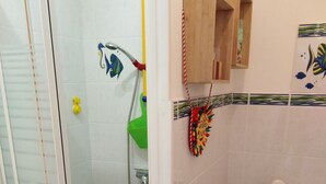 A bathroom with a glass-enclosed shower, a toilet, and a small wooden cabinet. - Small 30m2 house for 2 people on private property with swimming pool (Fréjus)