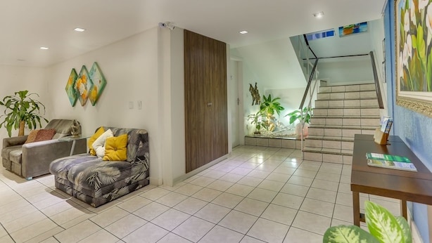 A modern living room with a sofa, a coffee table, and a staircase leading to an upper level. - Marazul Apart Hotel (Florianópolis)