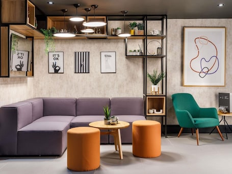 A modern living room with a sectional sofa, two round ottomans, a small wooden table, and a green armchair.