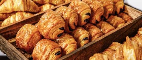 A wooden tray filled with golden-brown croissants.