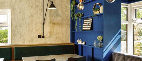 A seating area with a table and chairs, a bookshelf with decorative items, and a pendant light.