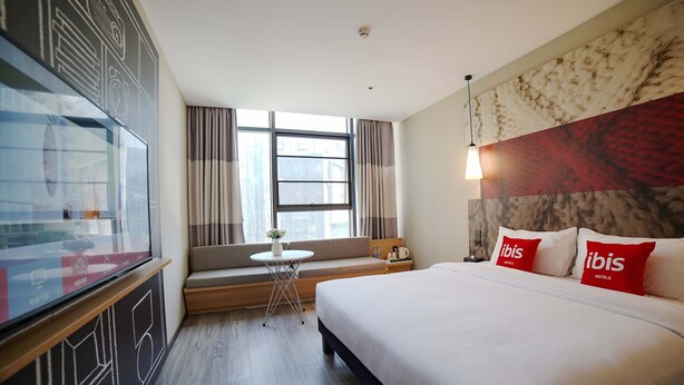 A hotel room with a large bed, a small round table, a sofa, and a TV. - Ibis Chengdu Hi-Tech Zone Longhu Hotel (Chengdu)