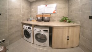 A laundry area with two washing machines, a wooden cabinet, and a sign on the wall.
