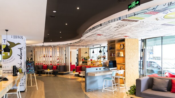 A modern interior with a curved counter, seating areas, and a wall with various writings.