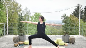 A person performing a yoga pose on a mat outdoors with a scenic view in the background. - Habitat Esslingen (Esslingen)