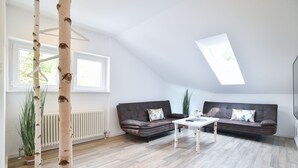 A modern living room with a loft-style ceiling, two dark brown sofas, a white coffee table, and birch tree sculptures. - Habitat Esslingen (Esslingen)