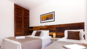 Une chambre d’hôtel avec deux lits, des têtes de lit en bois, une petite table de chevet avec une lampe et un tableau encadré au mur.