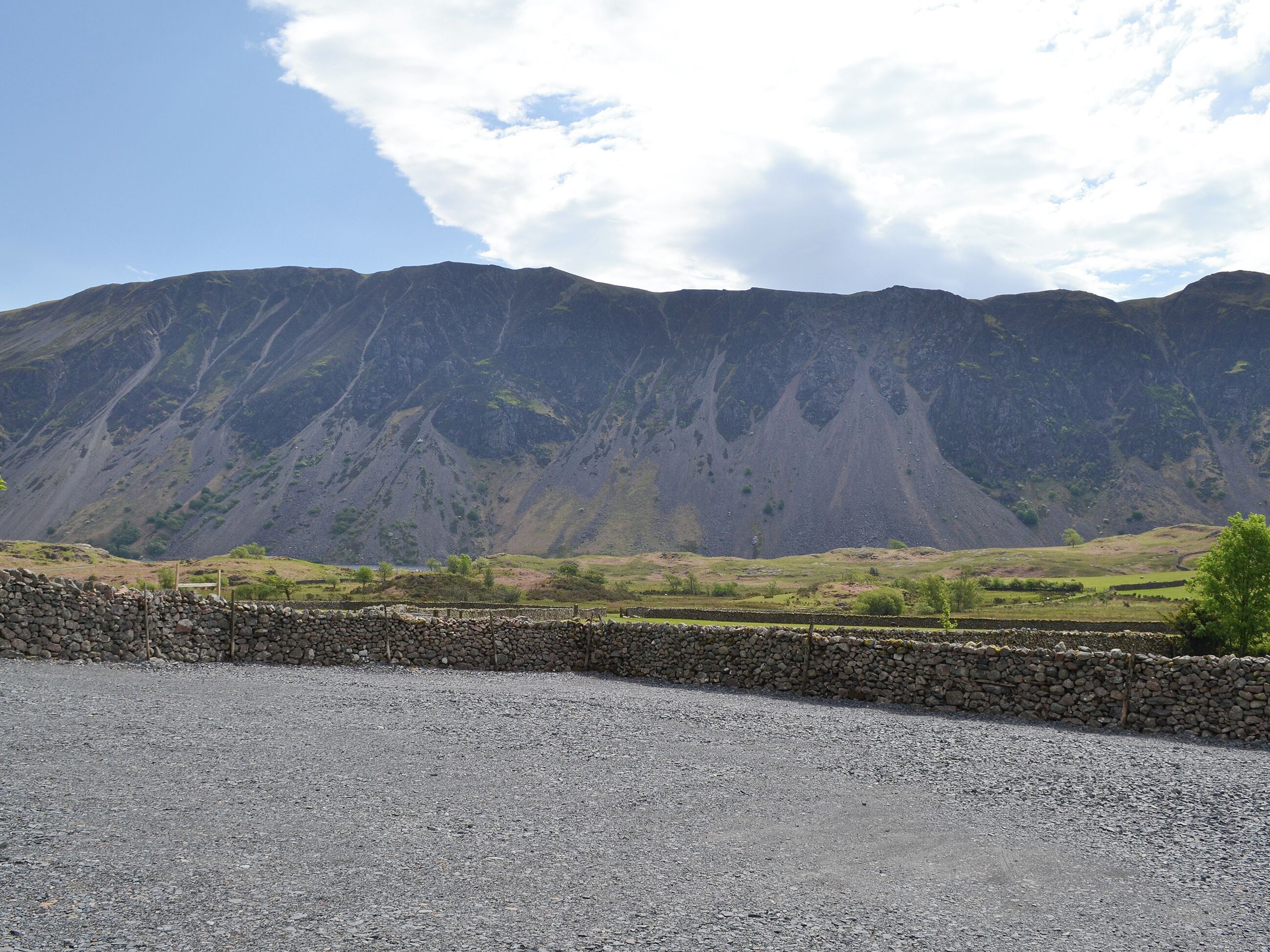 Een bergachtig landschap met een stenen muur op de voorgrond.