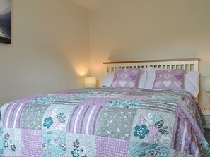 A bed with a floral quilt, a wooden headboard, and two bedside lamps.