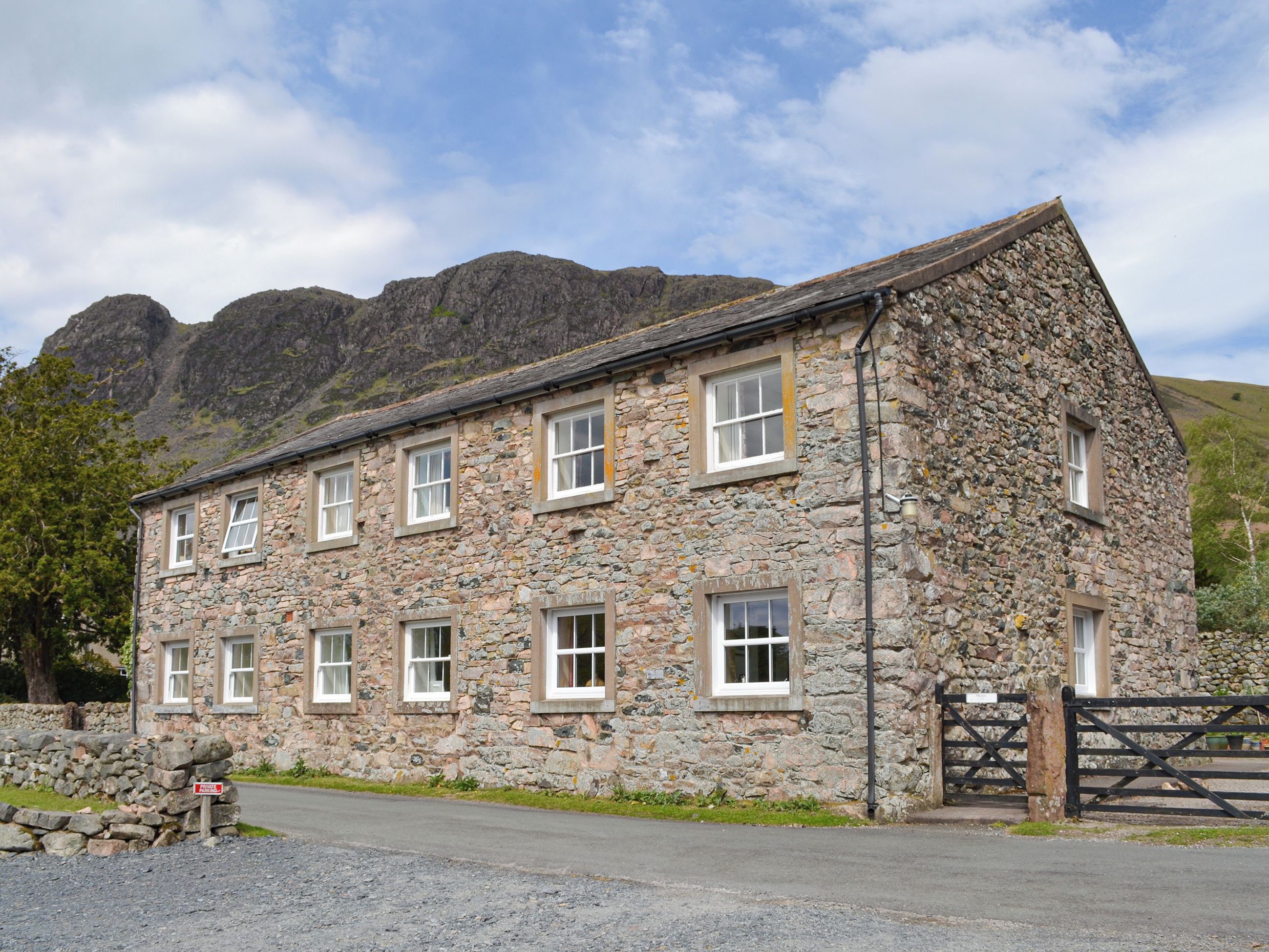 A stone building with multiple windows and a gated entrance.