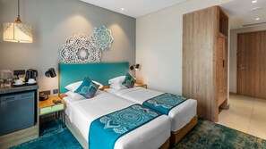 A hotel room with a bed, bedside tables, a desk with a coffee maker, and a wardrobe.
