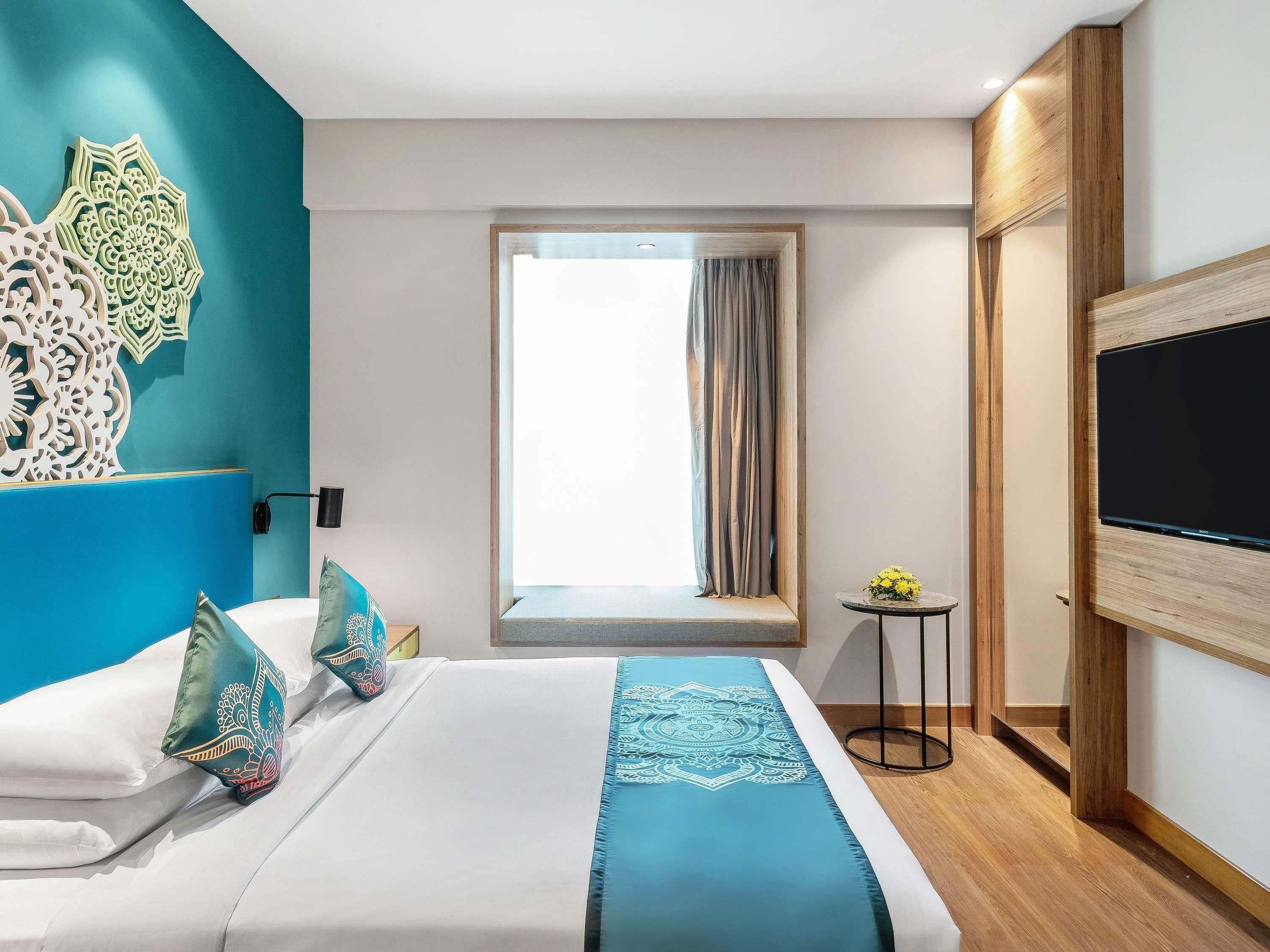 Ein Hotelzimmer mit Bett, Fernseher, Fenster mit Vorhängen und einer Wanddekoration.