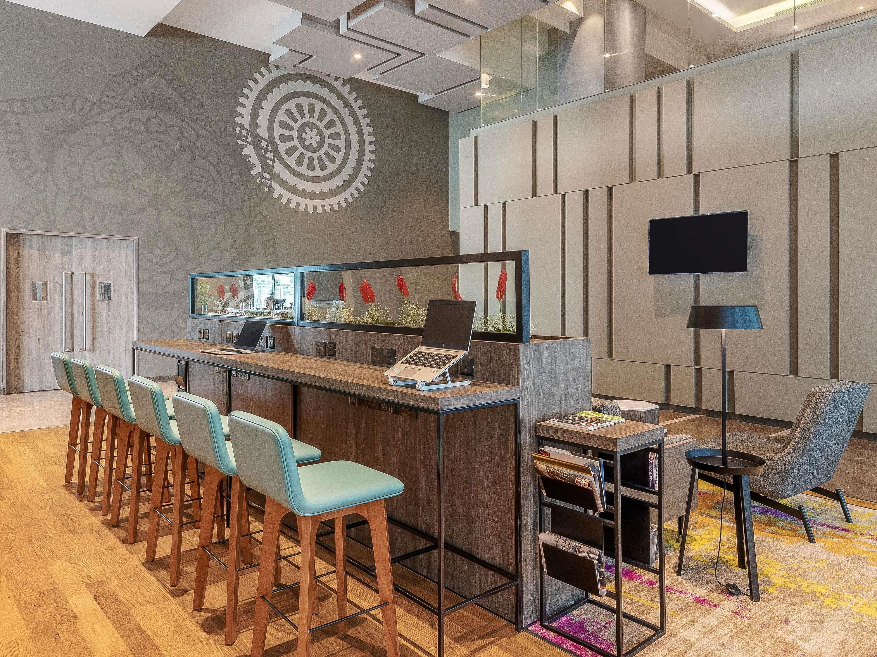 Uma área de recepção moderna com bar, assentos e televisão.