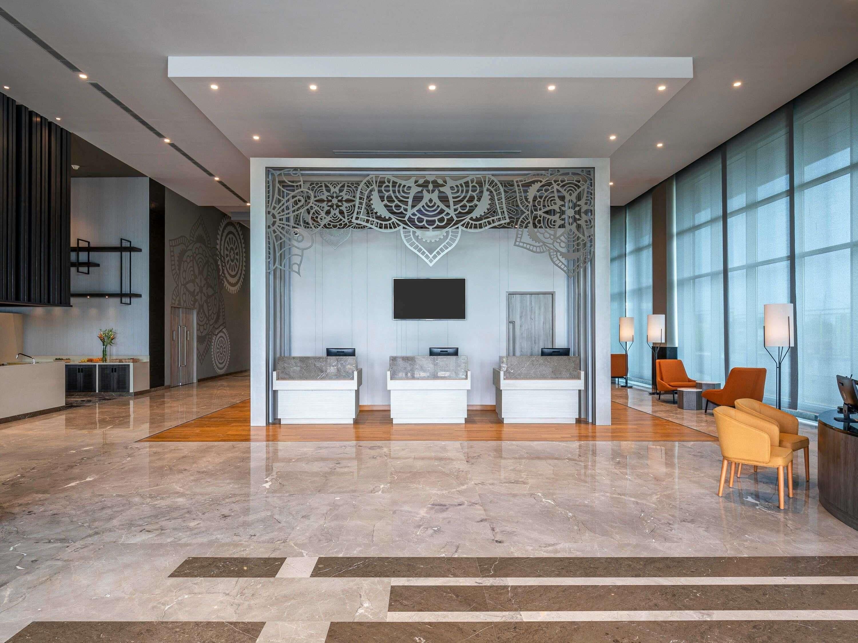 A modern lobby with a reception desk, seating area, and decorative wall art.