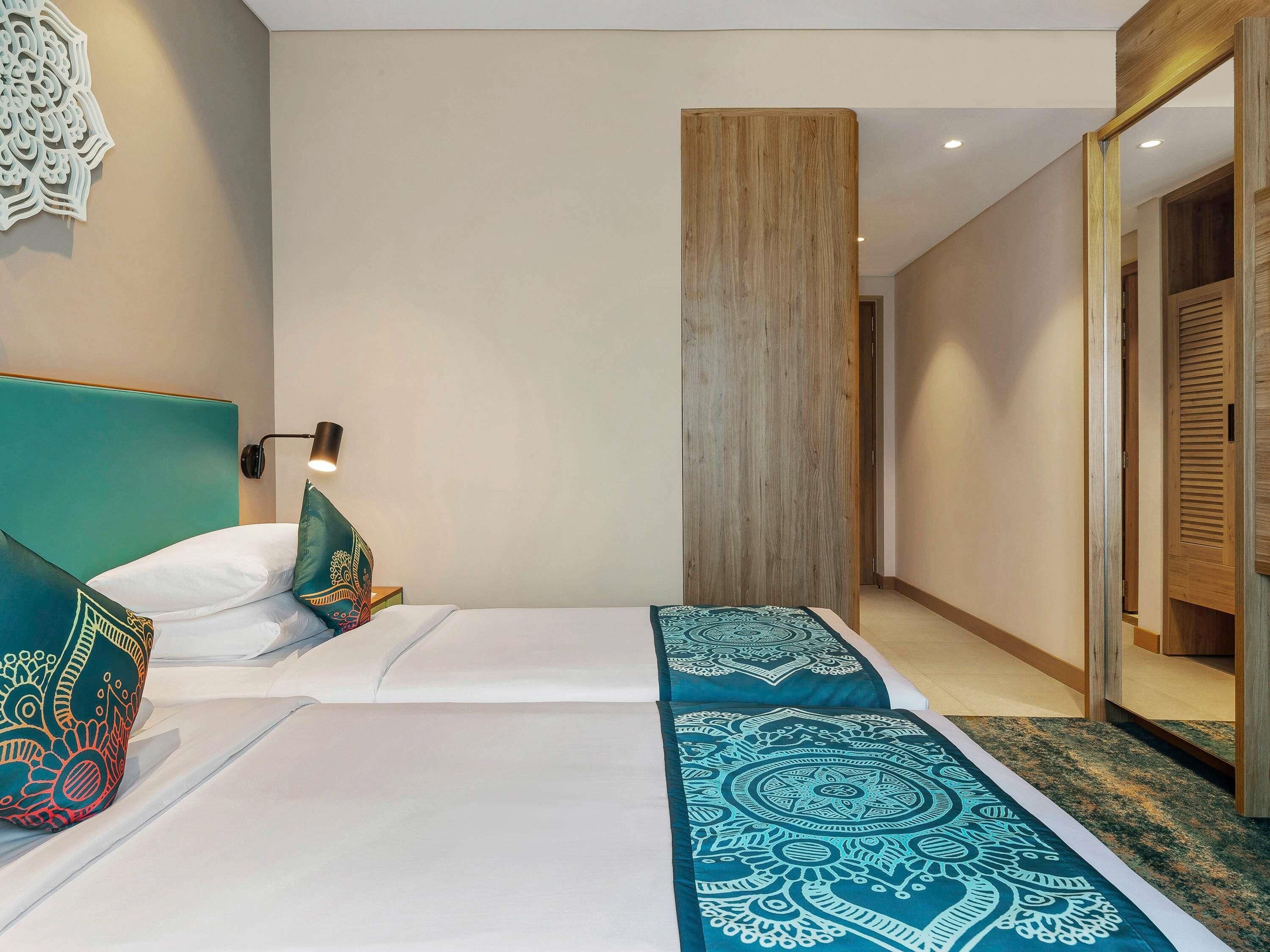 A hotel room with two beds, a wooden wardrobe, and a wall-mounted decorative piece.