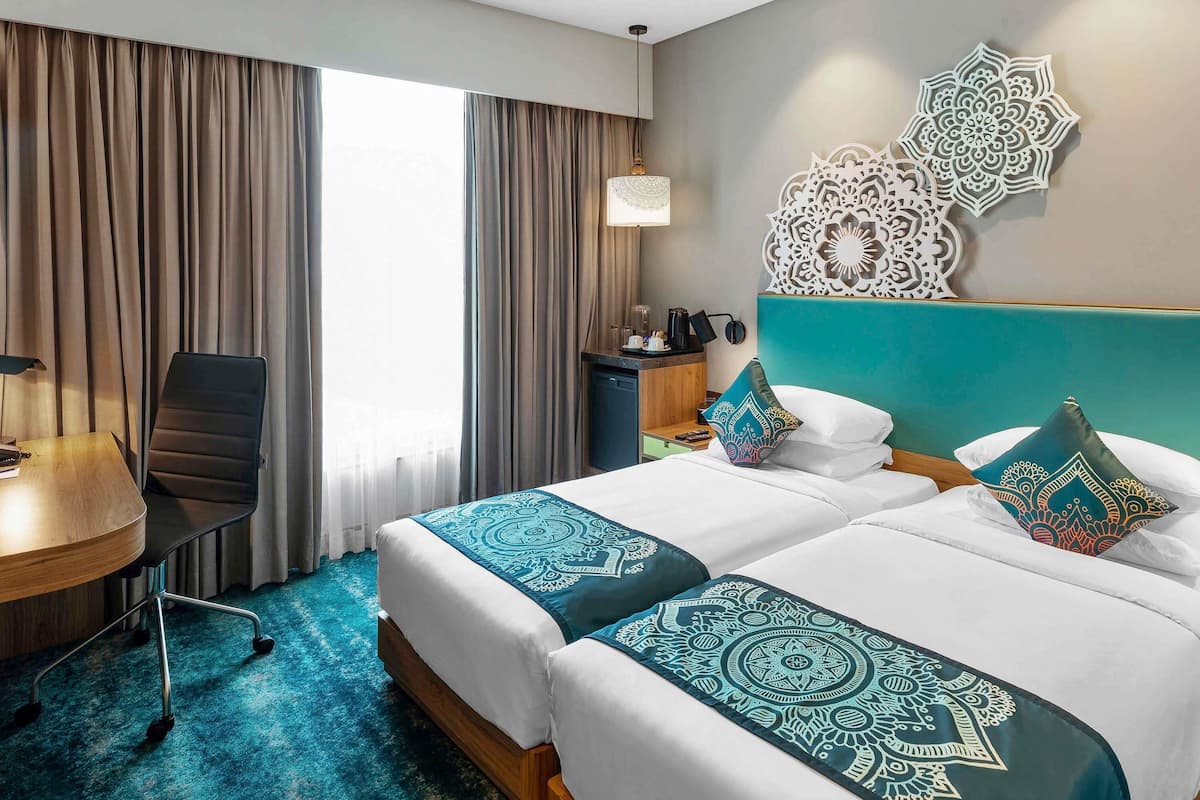 A hotel room with a bed, a desk, and a chair.
