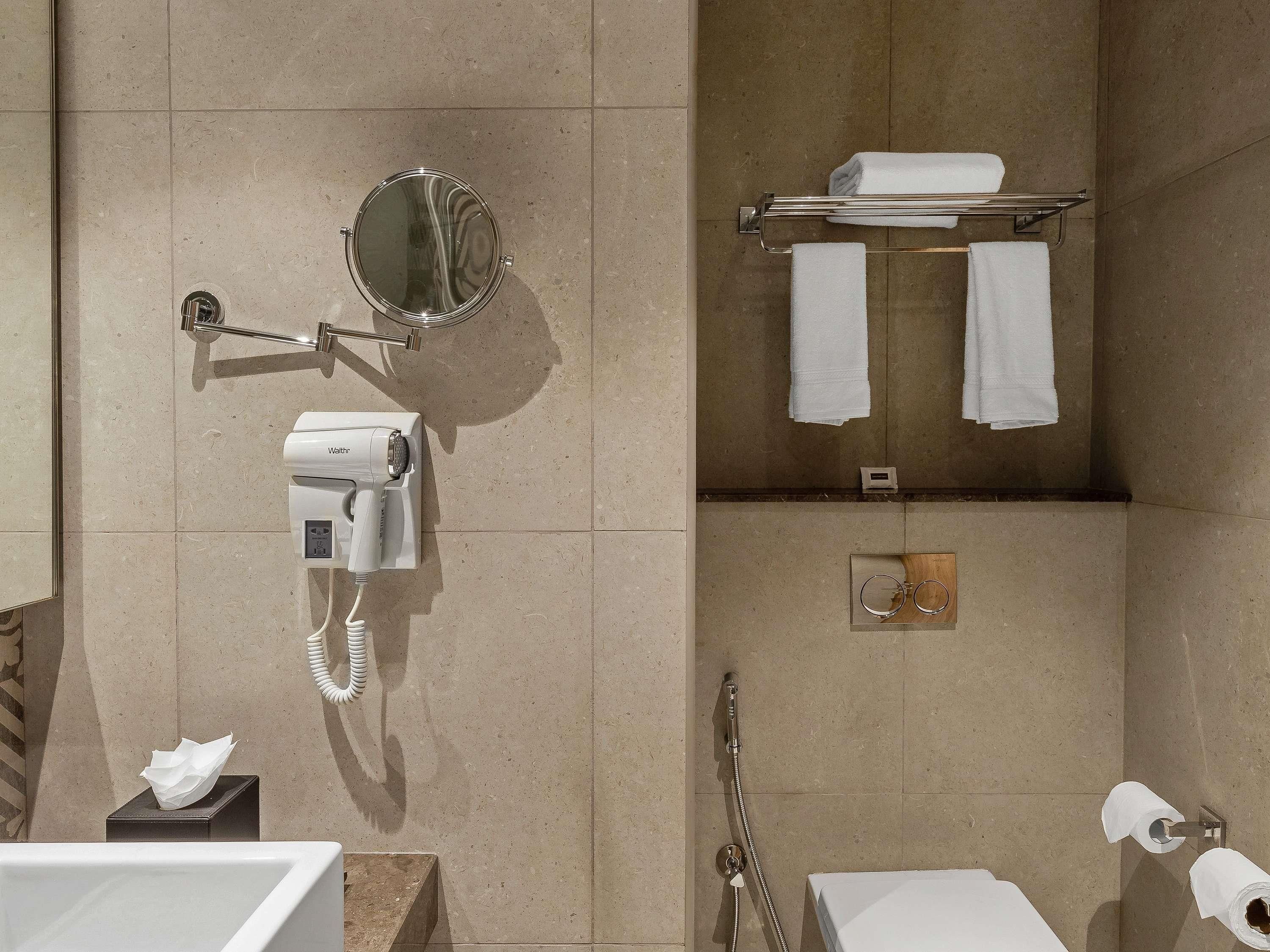 Une salle de bain équipée d’un sèche-cheveux, d’un porte-serviettes, d’un miroir et d’une douche.