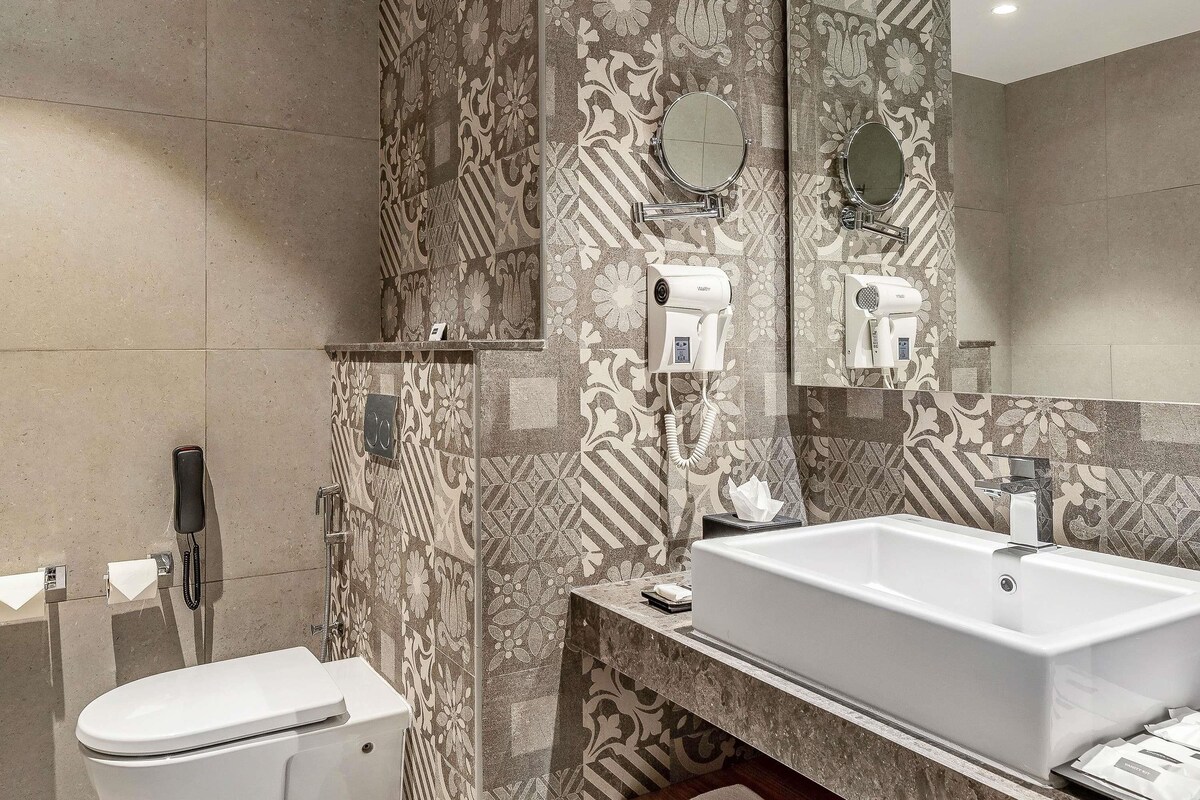 A bathroom with a toilet, a sink, and a mirror.
