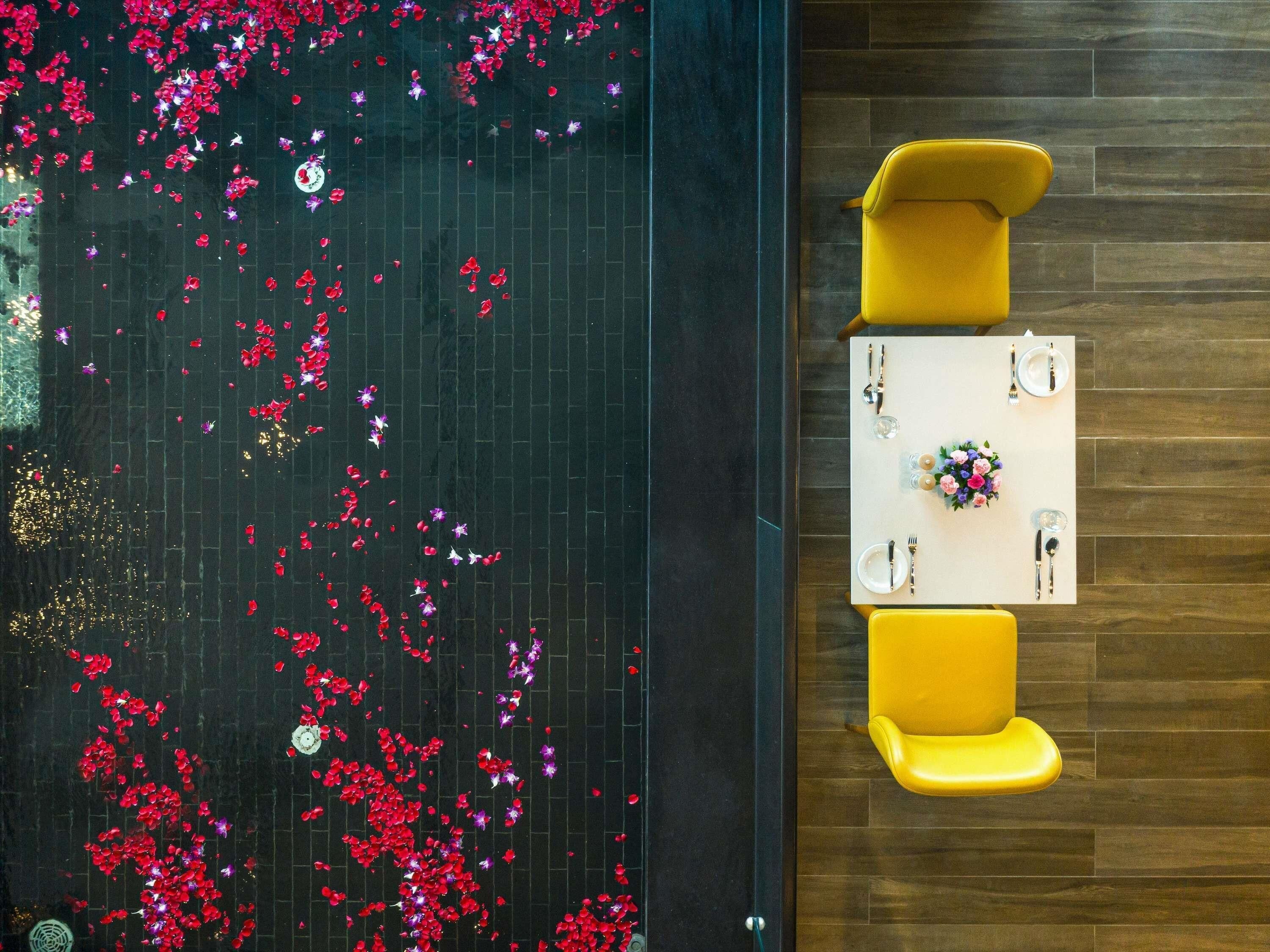 A dining area with a table set for two, yellow chairs, and a dark floor.