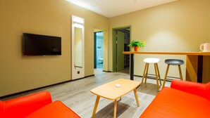 Una habitación moderna con televisión, una mesita, dos sillas y un banco.