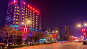 Un hotel moderno de altura con señalización iluminada, fachada bien iluminada y vistas claras del entorno urbano.