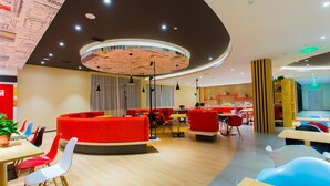 Un interior moderno con mesas redondas, asientos rojos y un diseño de techo original.