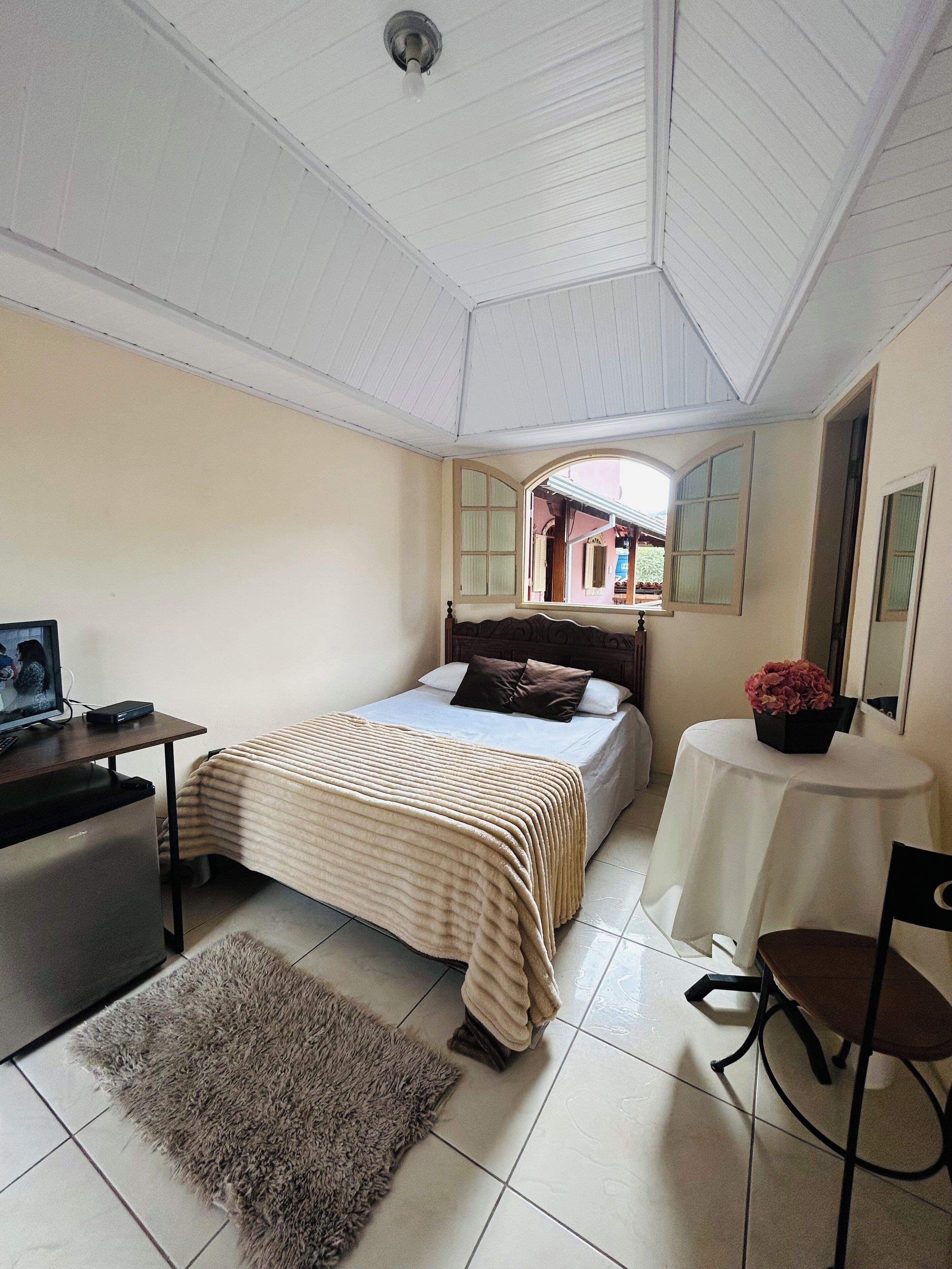 Une chambre à coucher avec un lit, un bureau, une chaise, une petite table et un miroir.