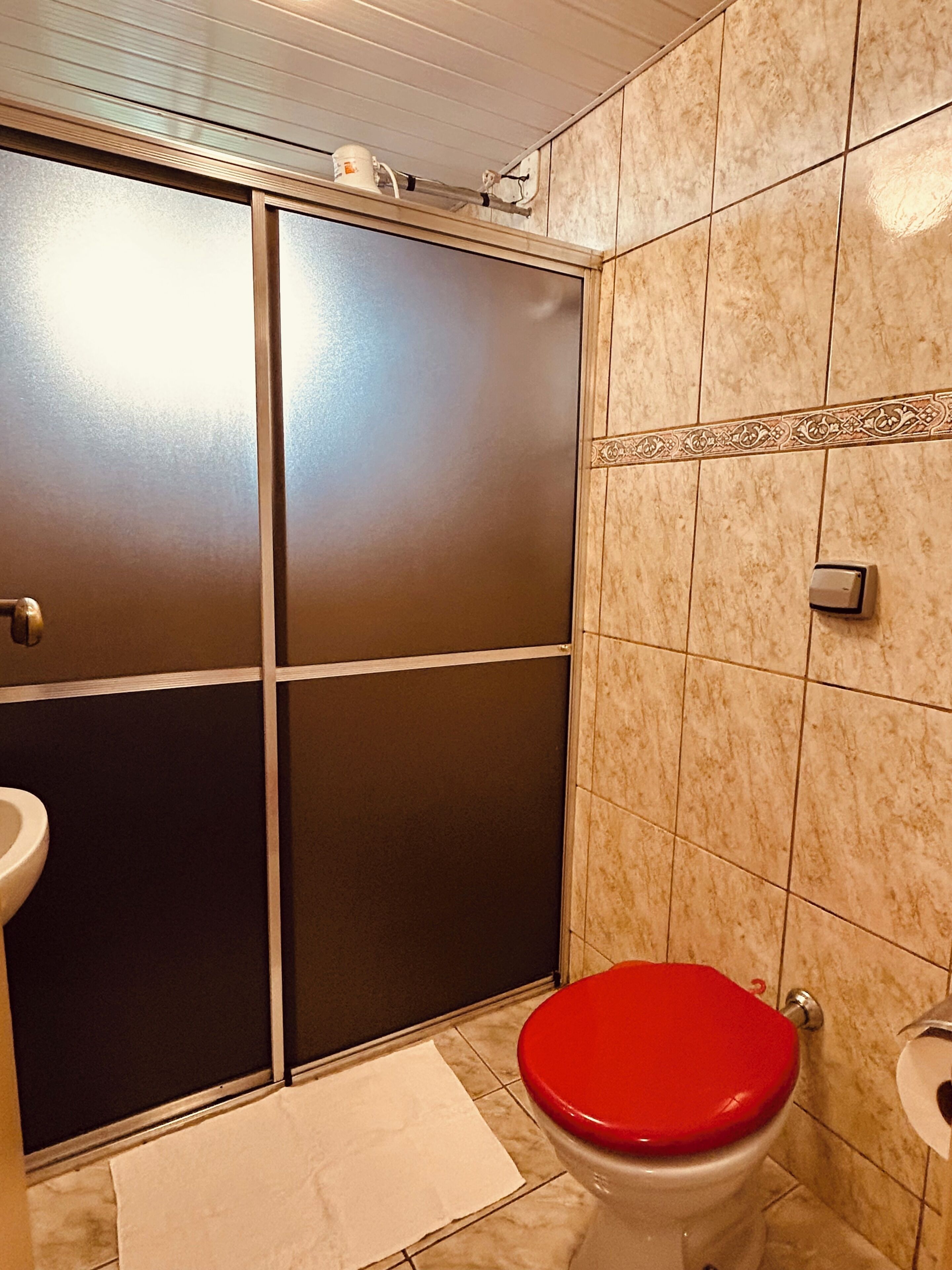 Un baño con inodoro, lavamanos y zona de ducha con puerta corredera.