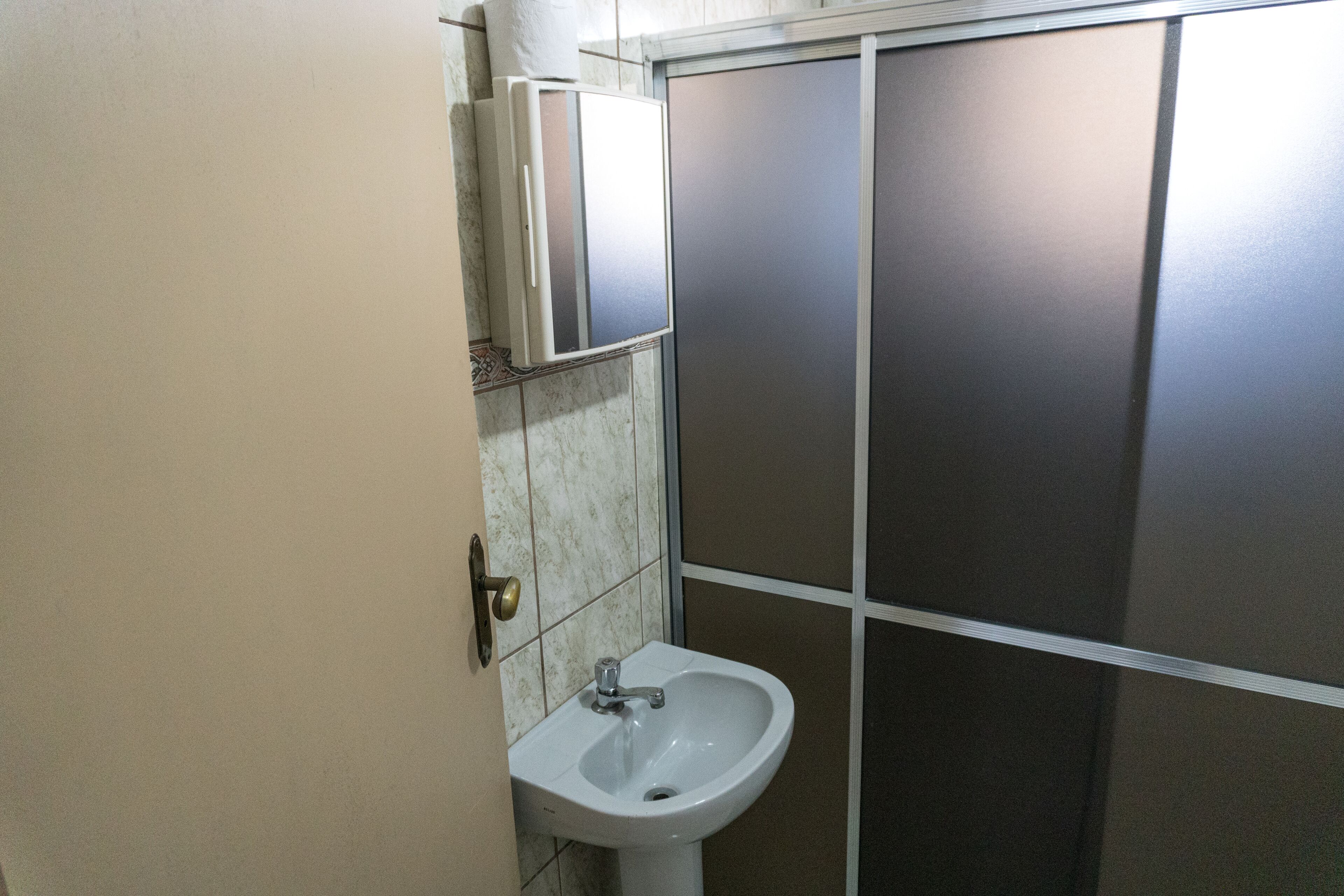 Un baño con un lavamanos blanco, un espejo y un dispensador de toallas.