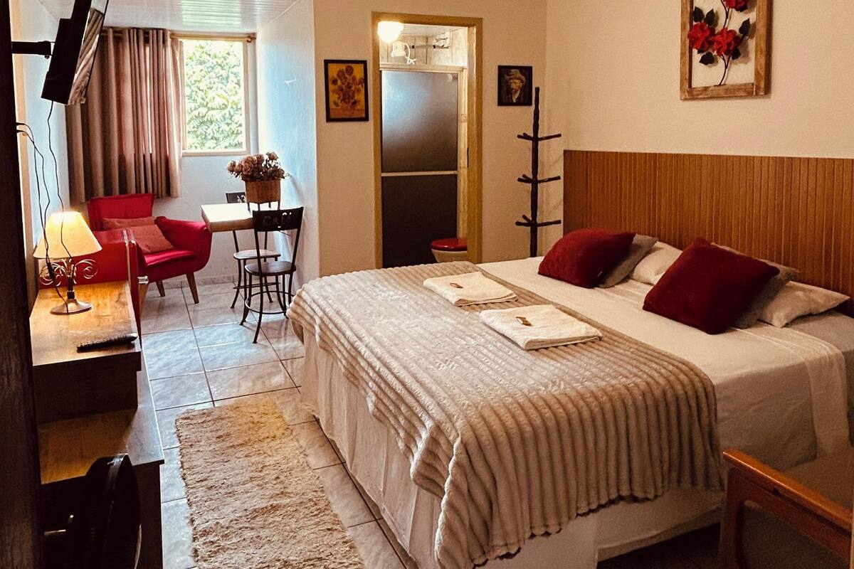 Ein Hotelzimmer mit Bett, Schreibtisch, Stuhl, Fernseher und einem Fenster mit Vorhängen.