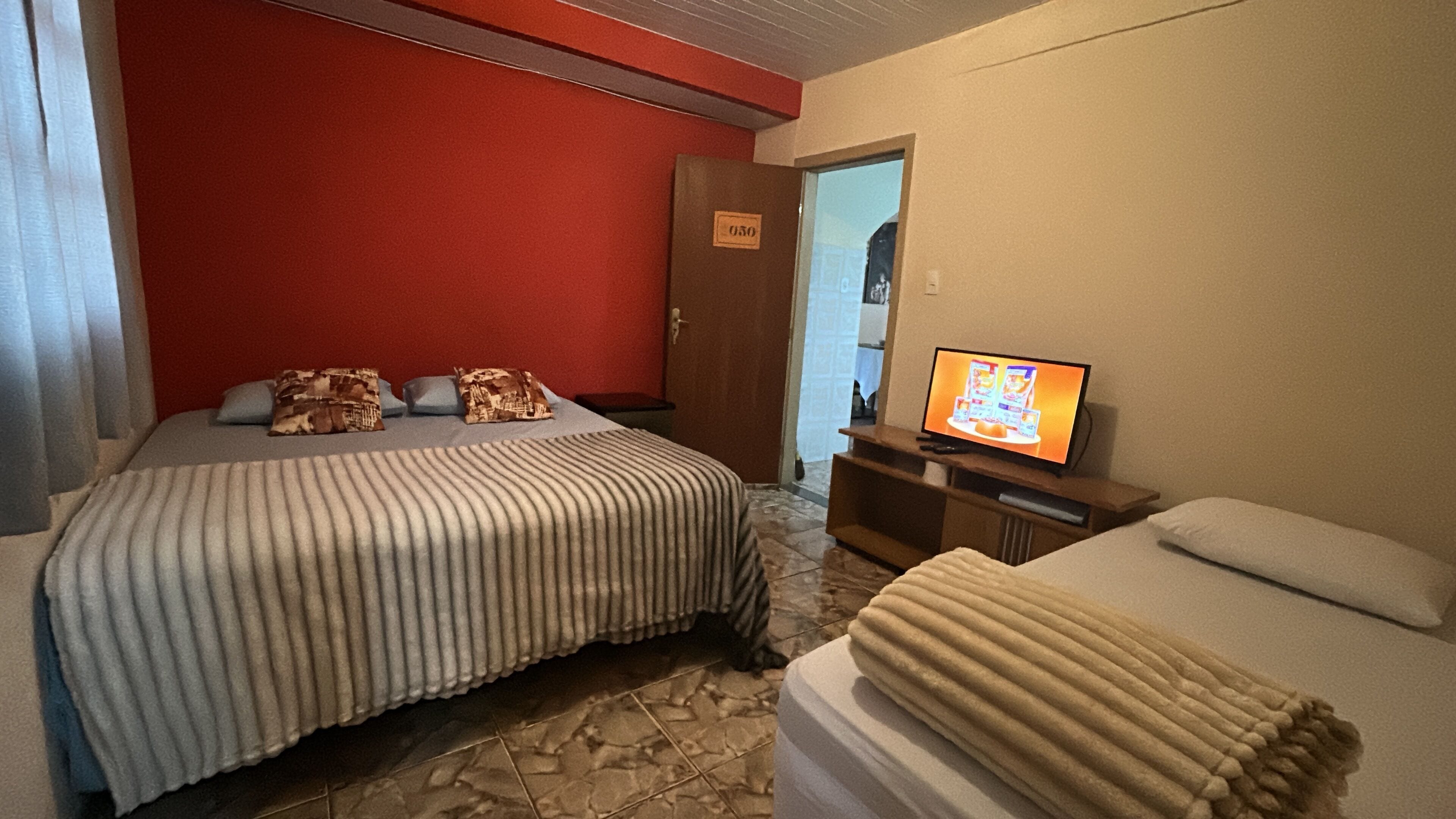 Ein Hotelzimmer mit einem Bett, einem Fernseher, einer Tür und einem kleinen Tisch.