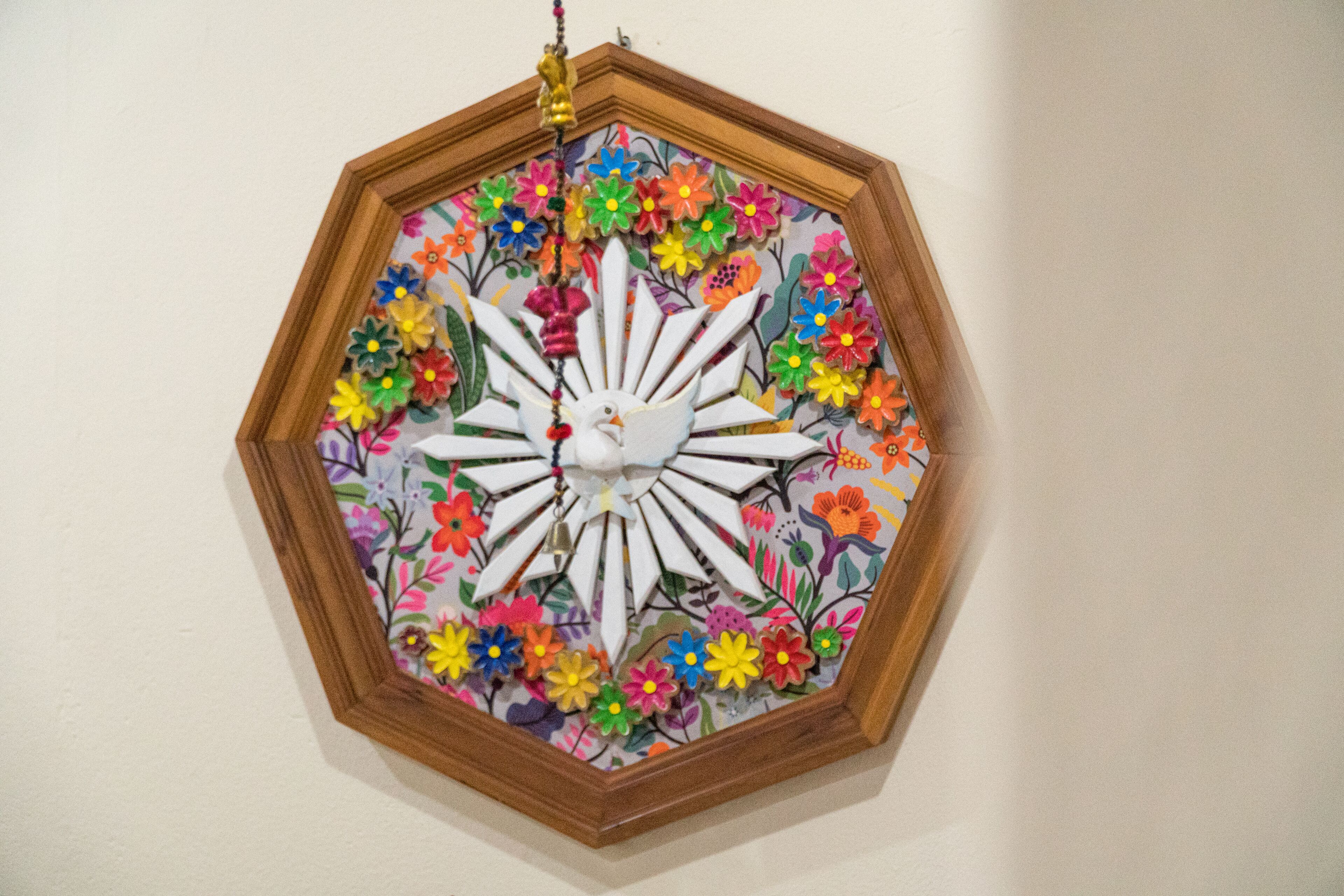 A framed artwork with a central white bird surrounded by colorful flowers.
