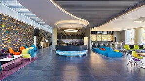 Un lobby moderno con mostrador de recepción, zonas de estar y una pared grande con un diseño geométrico.