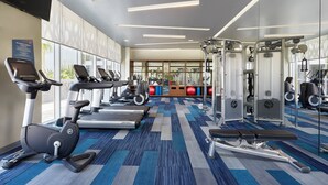 Un gimnasio con cintas de correr, elípticas y equipos de levantamiento de pesas.