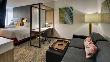 A hotel room with a bed, a desk, a sofa, and a TV.