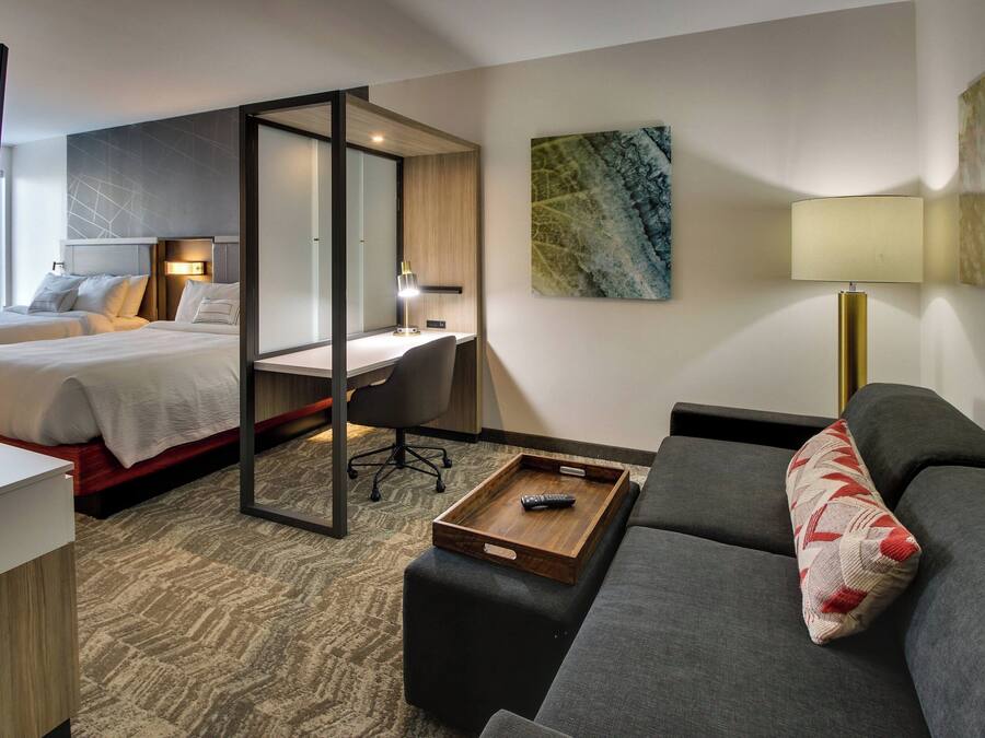 A hotel room with a bed, a desk, a sofa, and a TV.