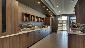 Une cuisine moderne avec des meubles en bois, un bar pour prendre le petit-déjeuner et une vue sur l’extérieur.