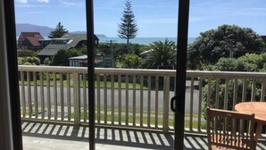 Um deck de madeira com vista para o oceano e montanhas.