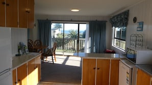 Uma cozinha com armários de madeira, uma mesa de jantar e vista para o exterior.