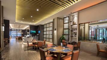 Un moderno vestíbulo de hotel con techo de madera, una zona de bar y diferentes disposiciones de asientos.