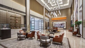 Un vestíbulo amplio con mobiliario moderno, una zona de estar central y detalles decorativos.