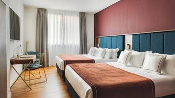 Une chambre d’hôtel avec deux lits, un bureau, une chaise, une télévision et une grande fenêtre avec des rideaux.